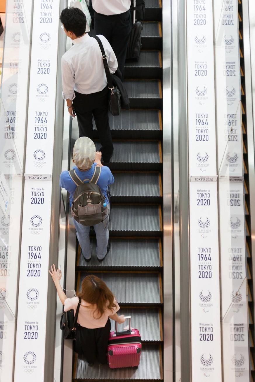Tokio 2020, Flughafen Haneda mit Olympiawerbung Travellers stand on escalator with Tokyo Olympic and Paralympic Games logos at Haneda-Airport Domestic Terminal 1 on August 30, 2016, Tokyo, Japan. Betw ...