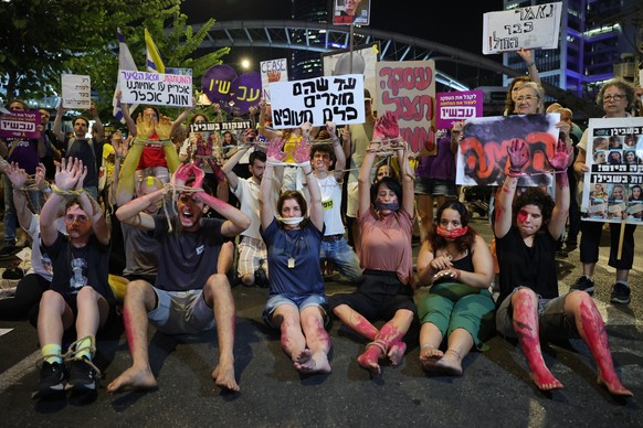 epa11596836 Demonstrators covered in fake blood with tied hands perform as Israeli hostages during a protest calling for a ceasefire and release of the Israeli hostages held by Hamas in Gaza, outside  ...