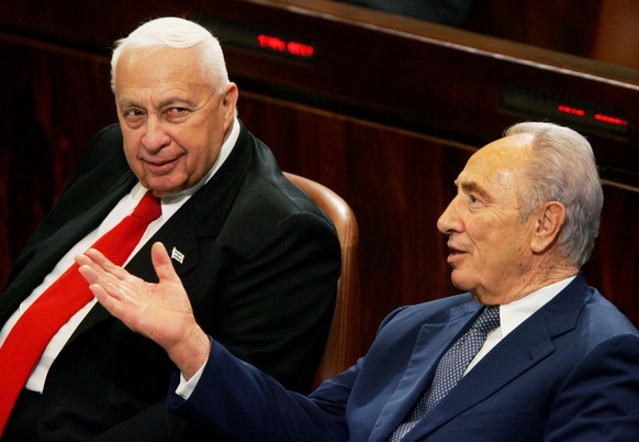 FILE - In this March 28, 2005, file photo, Israeli Prime Minister Ariel Sharon, left, talks with Vice Premier Shimon Peres during speeches prior to a vote in the Knesset, Israel's Parliament, in  ...