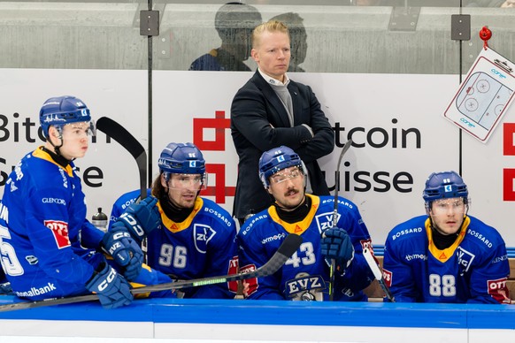 Head Coach Michael Liniger (EVZ), Mitte stehend, und Gregory Hofmann (EVZ), Daniel Vozenilek (EVZ), Jan Kovar (EVZ) und Sven Senteler (EVZ), von links, verfolgen das Spiel der Eishockey National Leagu ...