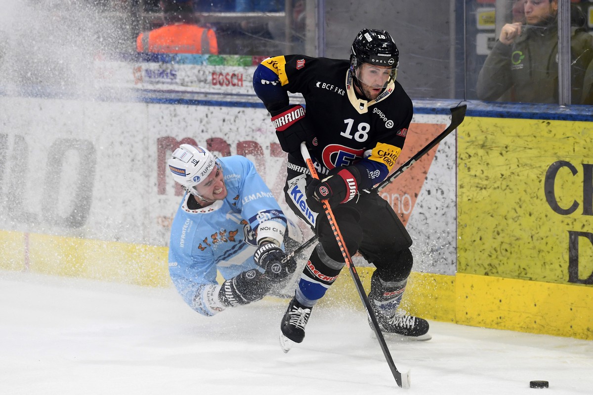 Ambri's player Alex Formenton left, fights for the puck with Fribourg's player Ryan Gunderson right, during the preliminary round game of National League (NL) Swiss Championship 2022/23 betw ...