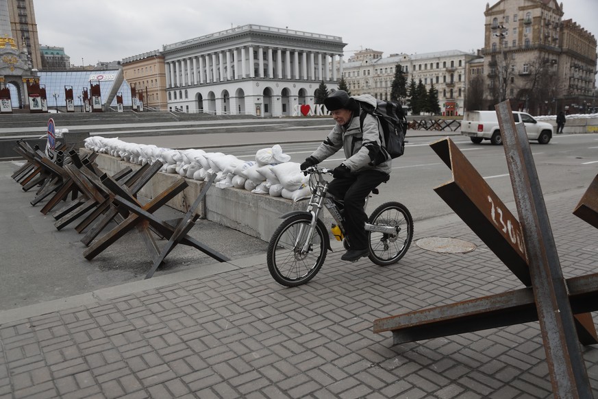 epa09805714 A man cycles past a roadblock in downtown Kyiv (Kiev), Ukraine, 06 March 2022. Russian troops entered Ukraine on 24 February leading to a massive exodus of Ukrainians as well as internal d ...