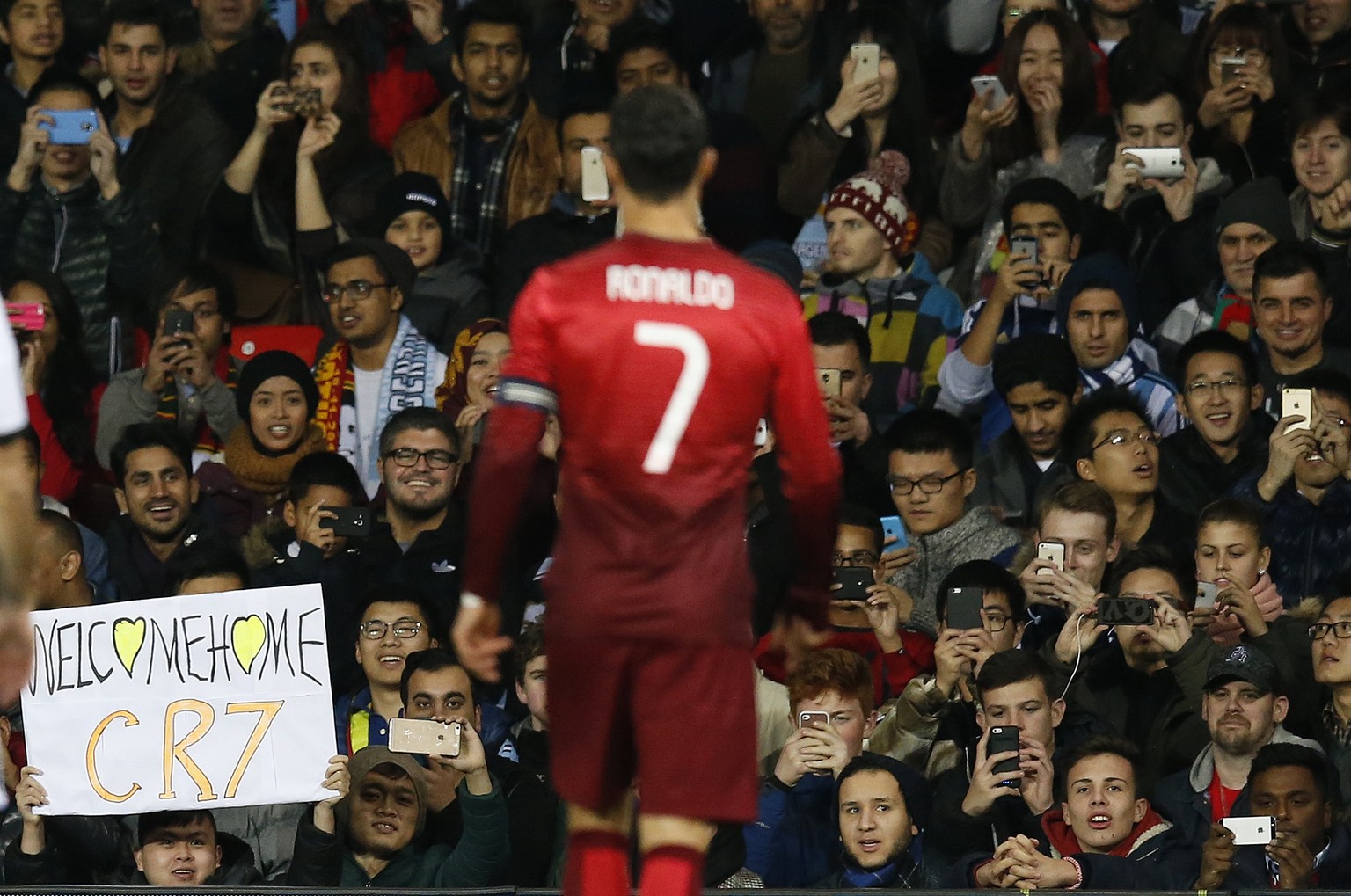 Fans take photos and hold a placard supporting Cristiano Ronaldo of Portugal, a former Manchester United player, during the International Friendly soccer match against Argentina at Old Trafford Stadiu ...