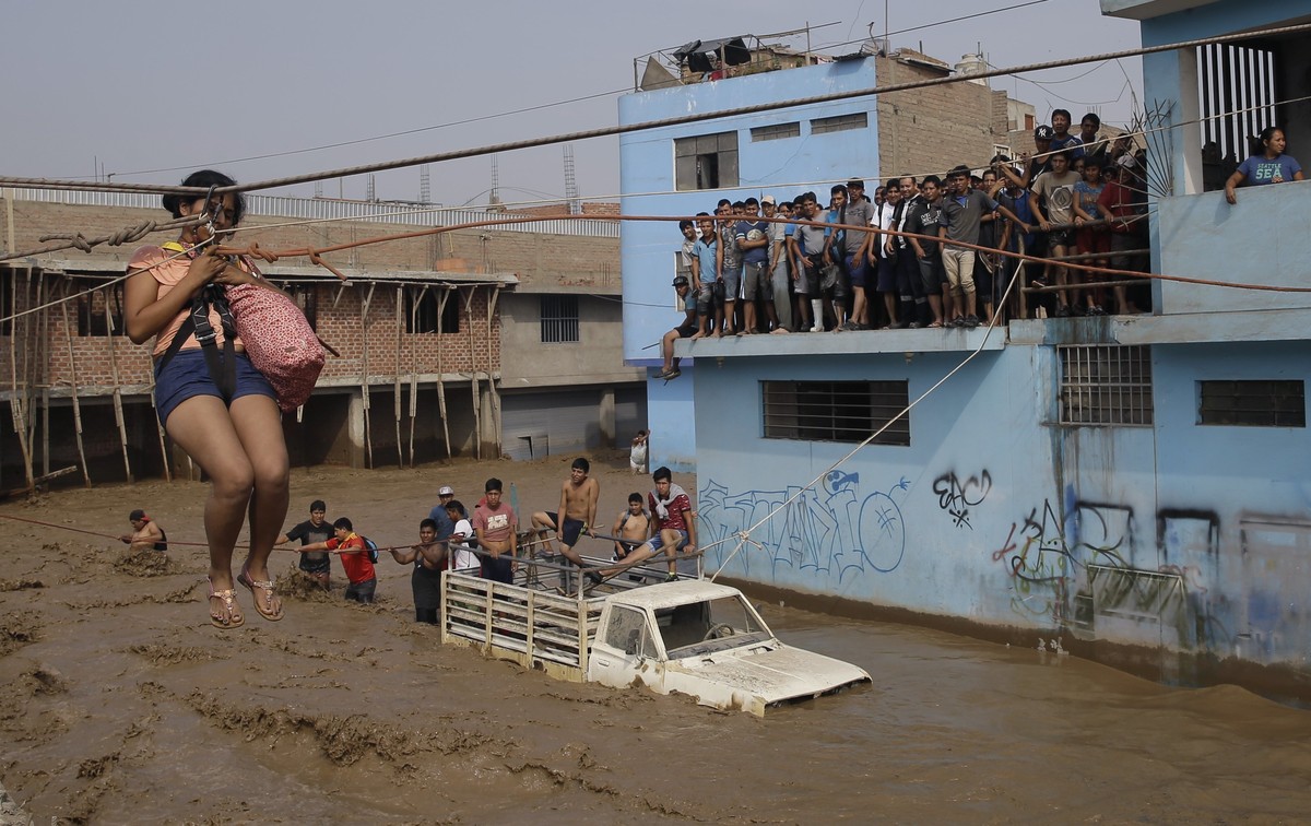A woman is pulled to safety in a zipline harness in Lima, Peru, Friday, March 17, 2017. Intense rains and mudslides over the past three days have wrought havoc around the Andean nation and caught resi ...