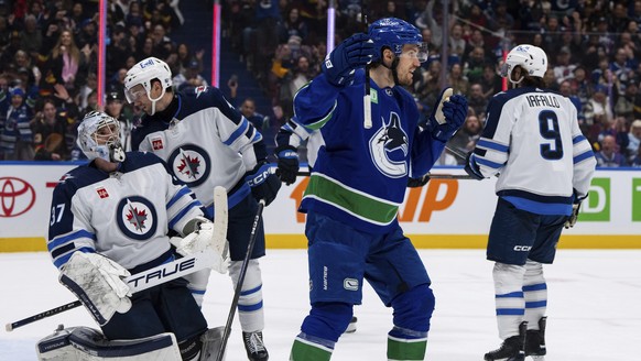 Winnipeg Jets goaltender Connor Hellebuyck (37) kneels on the ice as Neal Pionk (4) talks to him after Vancouver Canucks&#039; Pius Suter (24) scored during the third period of an NHL hockey game Satu ...