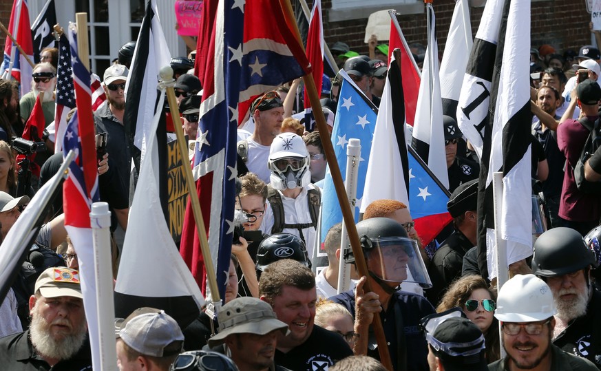 FILE - In this Saturday, Aug. 12, 2017, file photo, white nationalist demonstrators walk into the entrance of Lee Park surrounded by counter demonstrators in Charlottesville, Va. A former federal pros ...