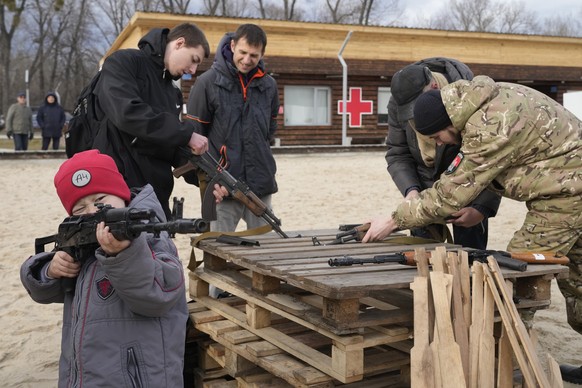 A boy plays with a weapon as an instructor shows a Kalashnikov assault rifle while training members of a Ukrainian far-right group train, in Kyiv, Ukraine, Sunday, Feb. 20, 2022. Russia extended milit ...