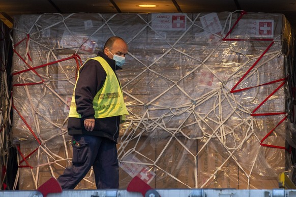 epa08376164 A worker unloads boxes containing facial masks and medical syringe pump from China from an aircraft Boeing 777-300ER (HB-JNK) of Swiss International Air Lines at the Geneve Aeroport, in Ge ...