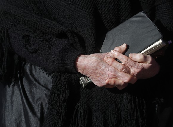 An elderly lady holds a book while standing outdoors during an outdoor Lutheran Church religious service in Csovar, Hungary, Sunday, Jan. 24, 2021. While Hungary has imposed strict COVID-19 restrictio ...