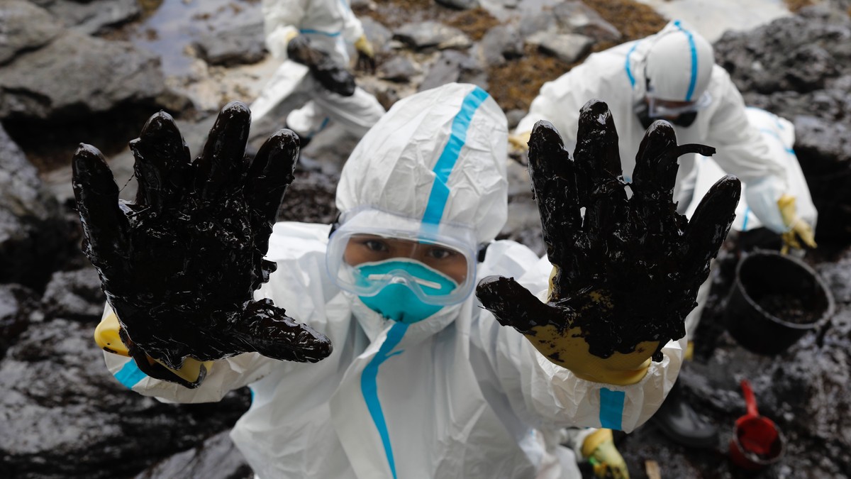 epa10505815 A Filipino fisherman wearing a protective suit displays oily waste on his hands along a beach in the coastal town of Pola, Mindoro island, Philippines, 06 March 2023. Affected fisherfolk w ...