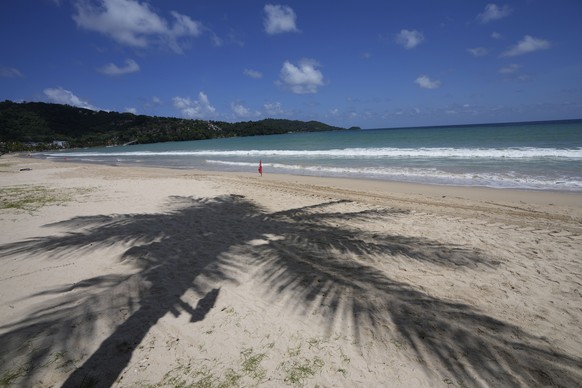 A palm tree casts a shadow on the empty tourist beach of Patong on Phuket, southern Thailand, Monday, June 28, 2021. Thailand's government will begin the &quot;Phuket Sandbox&quot; scheme to bring the tourists back to Phuket starting July 1. Even though coronavirus numbers are again rising around the rest of Thailand and prompting new lockdown measures, officials say there's too much at stake not to forge ahead with the plan to reopen the island to fully-vaccinated travelers. (AP Photo/Sakchai Lalit)