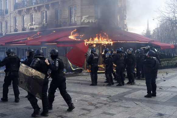 epa07442723 Riot police try to secure a perimeter in front of the Fouquet&#039;s restaurant on fire during the &#039;Act XVIII&#039; demonstration (the 18th consecutive national protest on a Saturday) ...