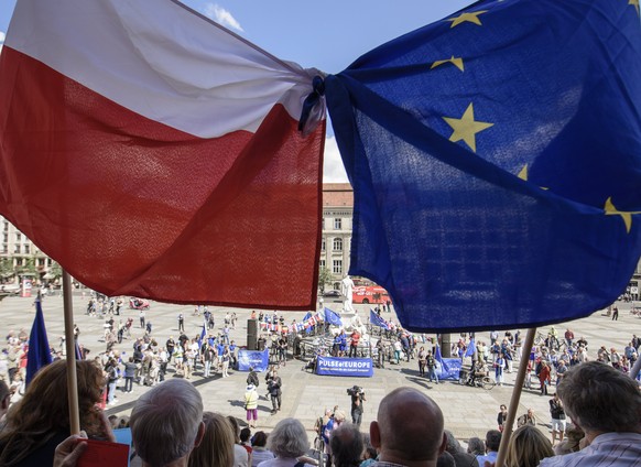 epa06128278 Participants of the monthly pro-European Union rally titled &#039;Pulse of Europe&#039;, hold flags in the national colors of Poland (L), and the European flag in front of the concert hall ...