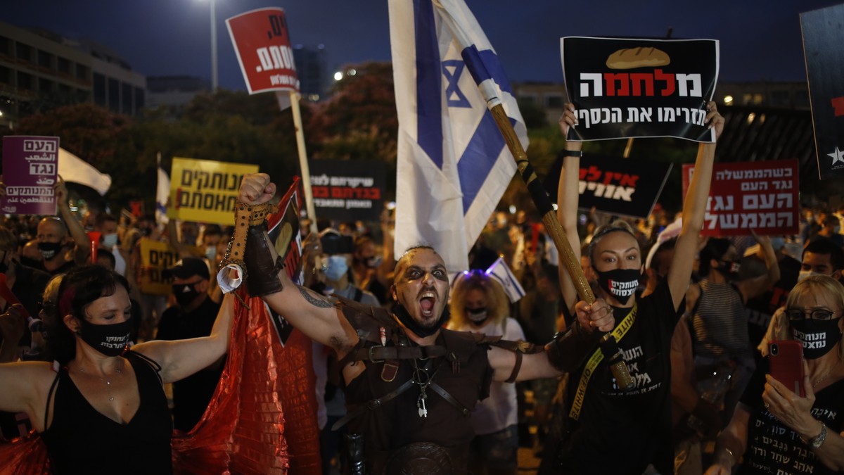 Protesters hold signs during a demonstration against Israel's government in Rabin square in Tel Aviv, Israel, Saturday, July 11, 2020. Thousands of Israelis gathered Saturday to protest the new g ...