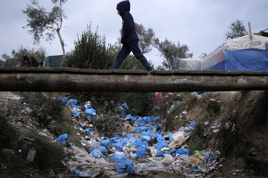A migrant boy walks over discarded garbage outside the Moria refugee camp on the northeastern Aegean island of Lesbos, Greece, on Tuesday, Jan. 21, 2020, as some businesses and public services are hol ...