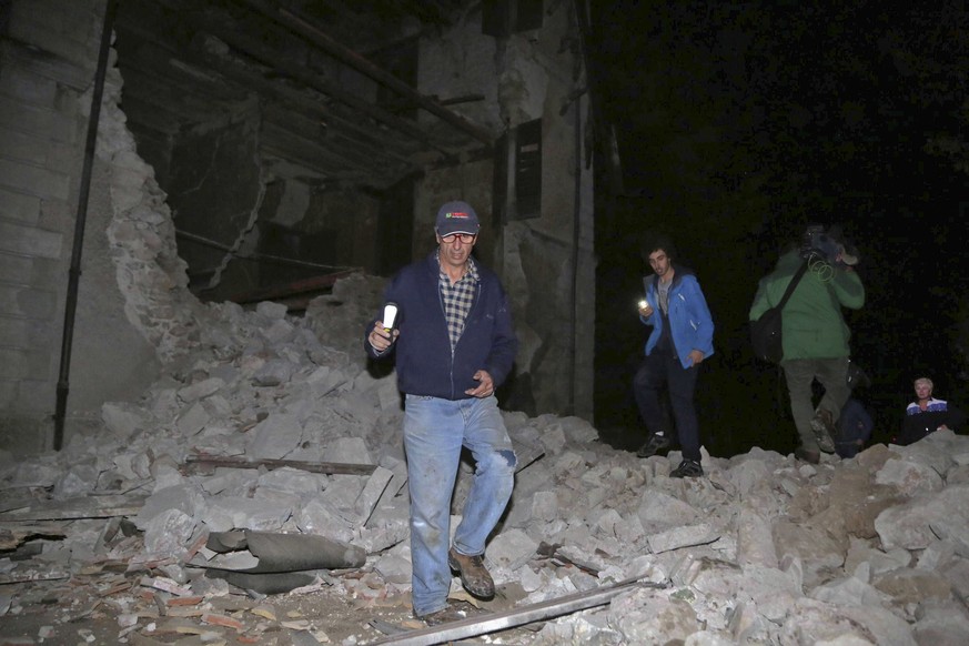 Residents walk past rubble in the village of Visso, central Italy, Wednesday, Oct. 26, 2016 following an earthquake. A pair of powerful aftershocks shook central Italy on Wednesday, knocking out power ...