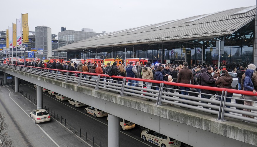 Travelers wait outside the Hamburg, northern Germany, airport Sunday, Feb. 12, 2017 after several people were injured by an unknown toxic that likely spread through the airports’ air conditioning syst ...