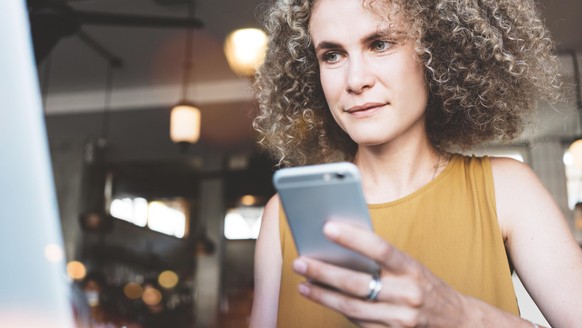 Frau mit Smartphone in Restaurant.