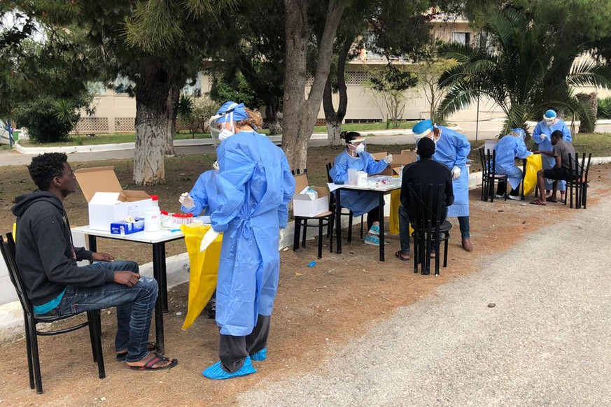 epa08373669 A handout photo made available by the Greek Organisation For The Public Health shows medical personnel make detection tests for Covid -19 to refugees from Somalia and Sudan hosted at a hot ...