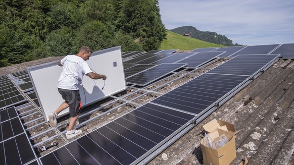 Der Solateur Jonas Huerlimann bei der Montage einer Solaranlage auf einer privat und gewerblich genutzten Halle in Stans, Kanton Nidwalden, am Donnerstag, 14. Juli 2022. Die Solaranlage hat eine Groes ...