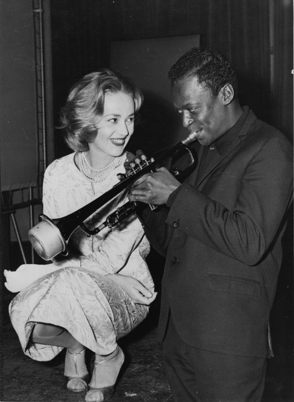 Jazz musician Miles Davis (1926 - 1991) playing his horn, with French actress Jeanne Moreau watching admiringly. (Photo by Keystone/Getty Images)