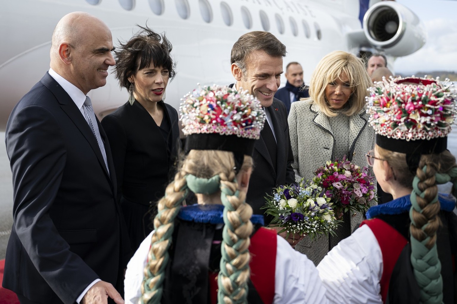 Switzerland President Alain Berset and his wife Muriel Zeender Berset, and French President Emmanuel Macron and his wife Brigitte Macron, from left to right, are welcomed by two young girl in traditio ...