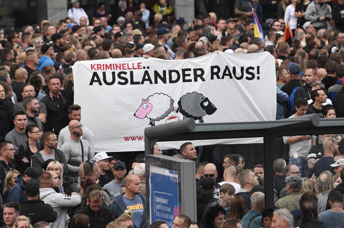epa06976998 Right wing protesters hold a banner reading: 'Criminal Foreigners Out!' as they gather at the place where a man was stabbed overnight 25 August 2018, in Chemnitz, Germany, 27 Aug ...