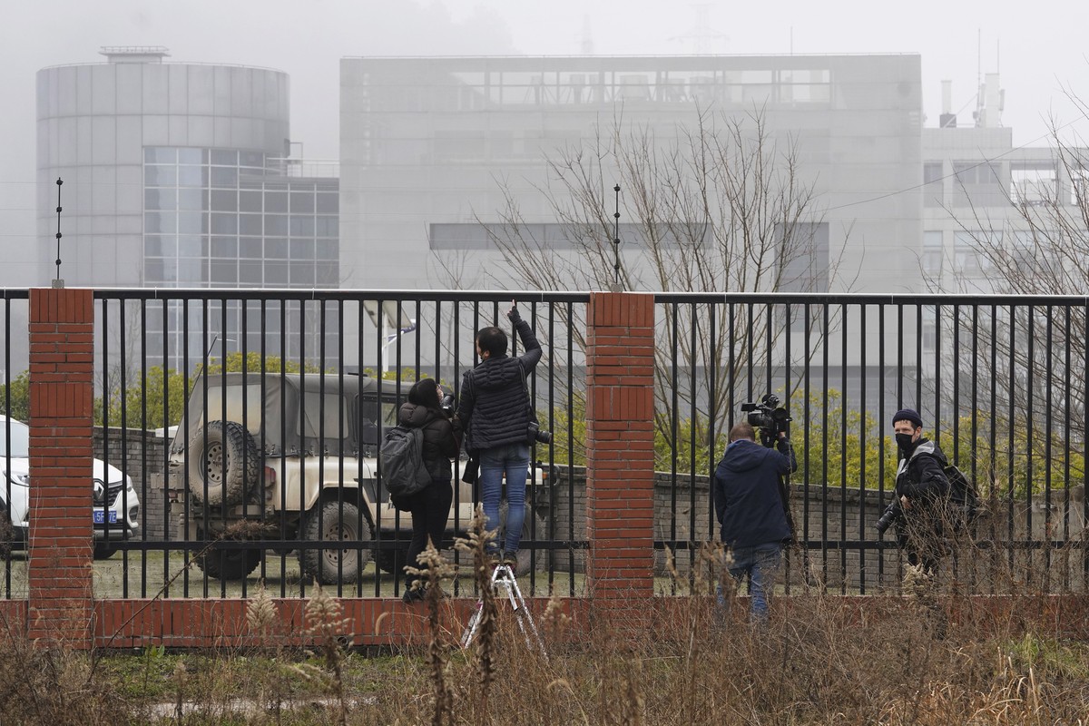 Journalists gather near an electric fence looking into the P4 Lab in the Wuhan Institute of Virology as the World Health Organization team visit on a field trip in Wuhan in China's Hubei province ...