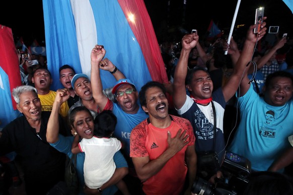 Opposition party supporters cheer and wave their party flags after Mahathir Mohamad claims the opposition party wins the General Election, broadcast on a large screen at a field in Kuala Lumpur, Malay ...