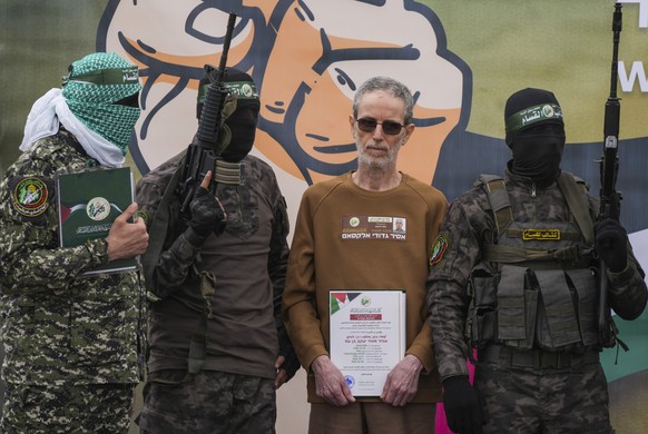 Israeli captive, Ohad Ben Ami, who has been held hostage by Hamas in Gaza since Oct. 7, 2023, is escorted by Hamas fighters before being handed over to the Red Cross in Deir al-Balah, central Gaza Str ...