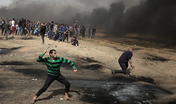 epa06667451 Palestinians protesters throw stones during clashes with Israeli topps near the border with Israel in the east of Gaza City on, 13 April 2018. According to local sources, more than 700 Pal ...