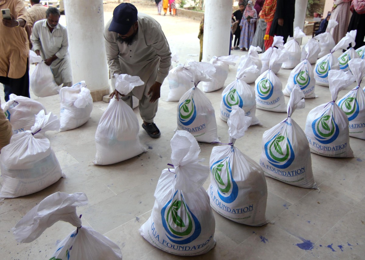 epa12819557 People receive free food rations distributed by the DUA foundation Pakistan, during the Muslim's fasting month of Ramadan, in Karachi, Pakistan, 14 March 2026. Muslims around the worl ...