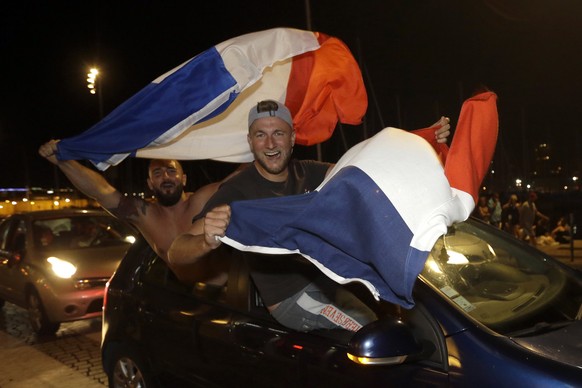French soccer fans wave national flags while celebrating their team victory after watching the semifinal match between France and Belgium at the 2018 soccer World Cup, in Marseille, southern France, T ...