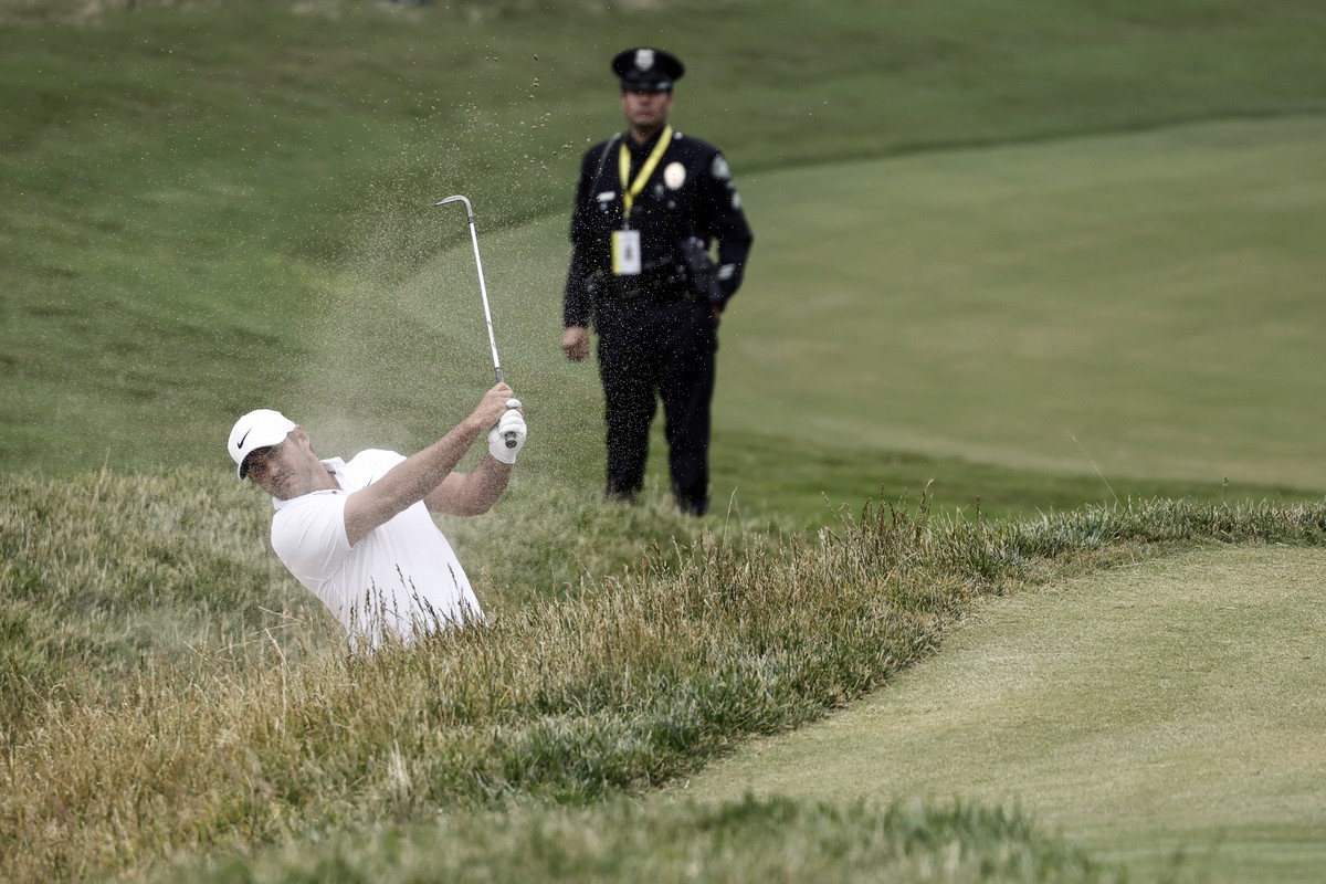 epa10691333 A police officer looks on as Brooks Koepka of the US practices on 7th hole during a practice round for the 2023 US Open golf tournament on the North Course of the Los Angeles Country Club  ...