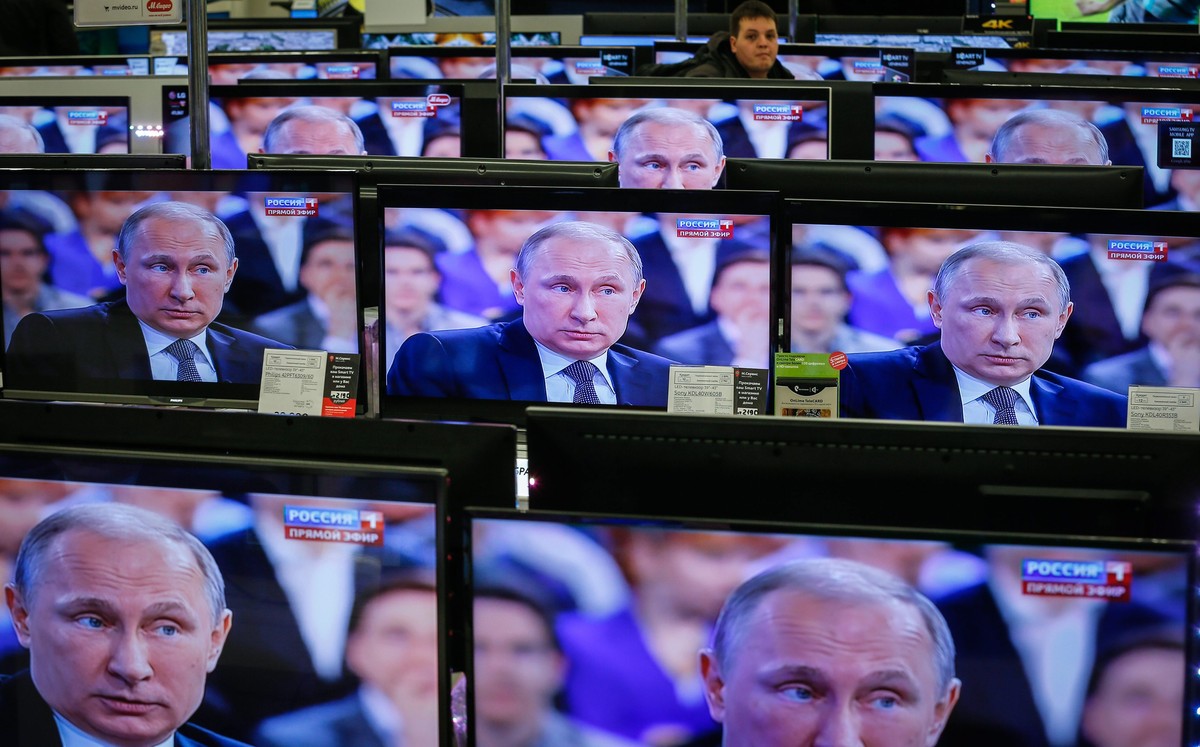 epaselect epa04707060 Russian man passes TV screens with Russian President Vladimir Putin an annual Q&amp;A (question-and-answer) nationwide live-broadcast TV and radio session in Moscow, Russia, 16 A ...