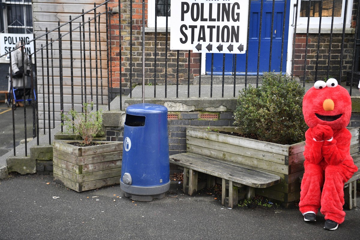 epa08064677 A protestor in an "Elmo" costume waits for opposition Labour Party Leader Jeremy Corbyn at a polling station during the general elections in London, Britain, 12 December 2019. Br ...