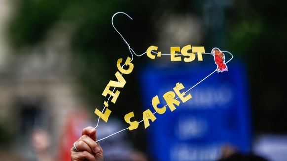 epa10035466 A woman holds a coat hanger (as a symbol for the era when woman used it for abortion when abortion was illegal) with a phrase that reads &#039;abortion is sacred&#039; during an abortion r ...