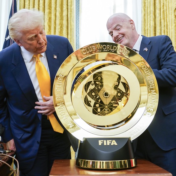 epa11947940 United States President Donald J Trump (L) stands with FIFA President Gianni Infantino and the Club World Cup trophy after signing an Executive Order setting up a task force on the World C ...