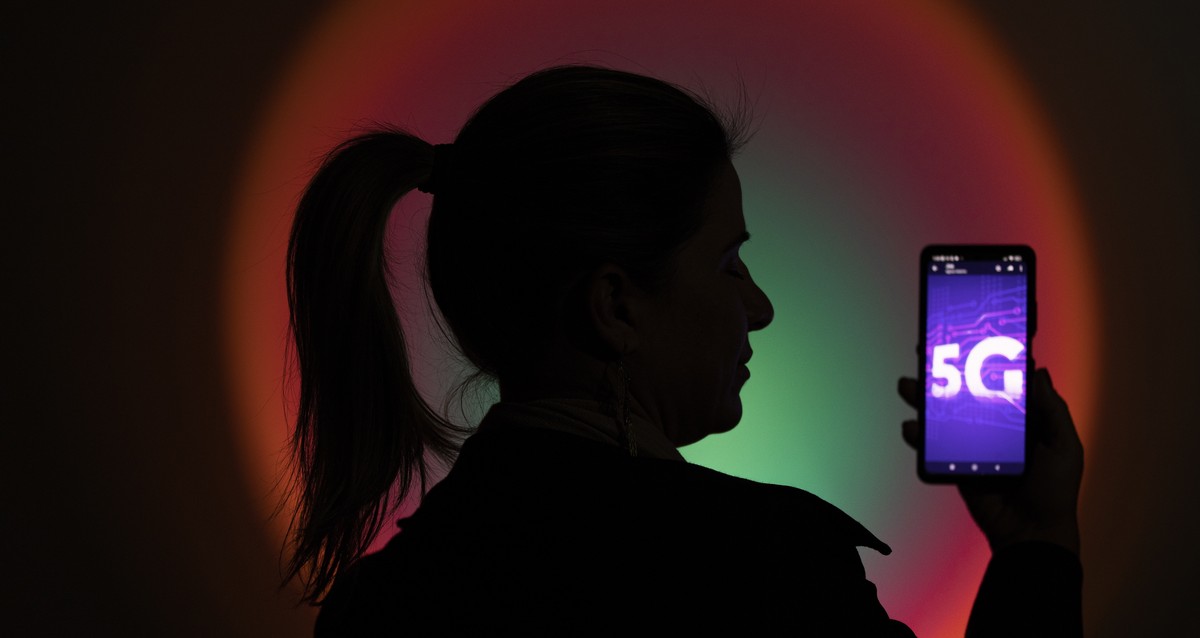epa10054966 A woman holds a cell phone with an image of the new 5G technology, in Brasilia, Brazil, 06 July 2022. The fifth generation of mobile internet (5G) is activated this Wednesday in Brazil. Br ...