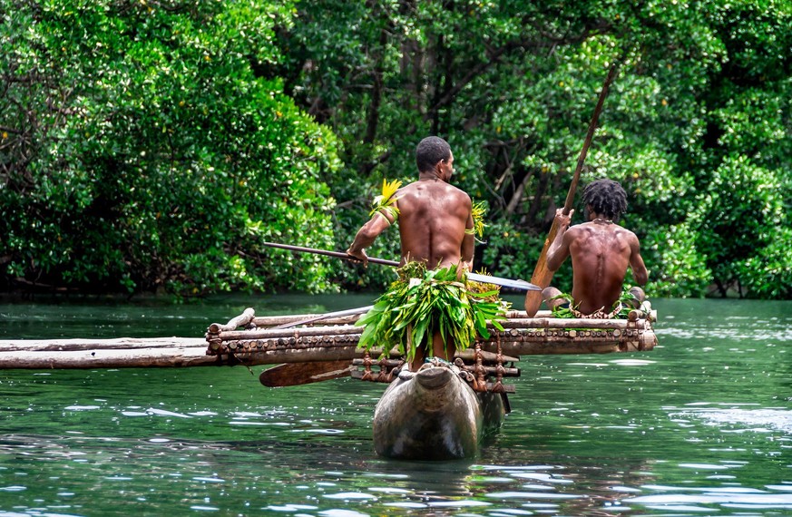 Zwei indigene Stammesmänner paddeln in einem traditionellen Kanu in der Nähe von Tufi auf Papua-Neuguinea.