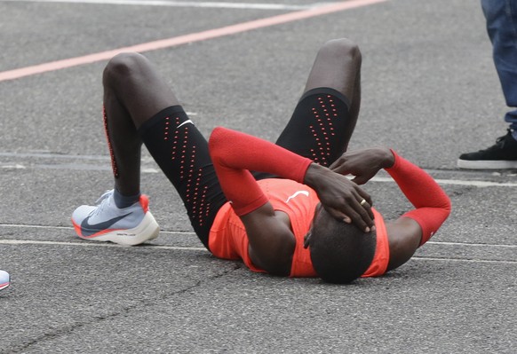 Olympic marathon champion Eliud Kipchoge lies down after crossing the finish line of a marathon at the Monza Formula One racetrack, Italy, Saturday, May 6, 2017. Kipchoge was 26 seconds from making hi ...