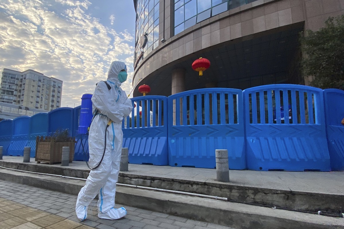 FILE - In this file photo dated Saturday, Feb. 6, 2021, a worker in protectively overalls and carrying disinfecting equipment walks outside the Wuhan Central Hospital where Li Wenliang, the whistleblo ...