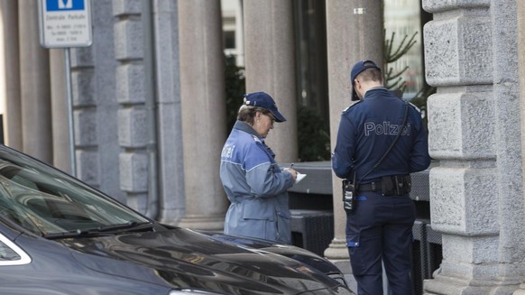 Ein Polizist und eine Polizistin verteilen Parkbussen am Stadthausquai am Mittwoch, 23. Dezember 2015, in Zuerich. (KEYSTONE/Patrick B. Kraemer)