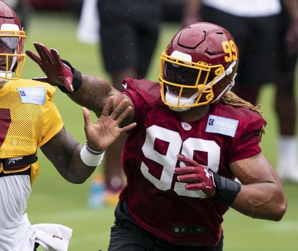 Washington quarterback Dwayne Haskins Jr. (7) passes under pressure from defensive end Chase Young (99) during an NFL football practice at FedEx Field, Monday, Aug. 31, 2020, in Washington. (AP Photo/ ...