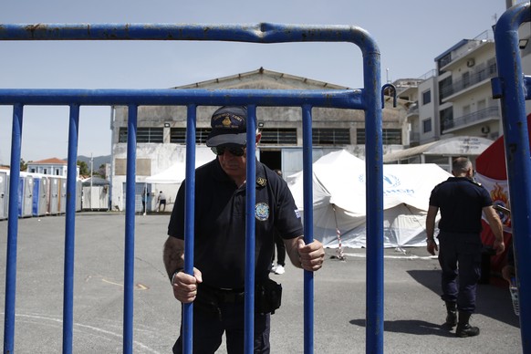 epa10692200 A Greek Coast Guard officer closes a gate in front of a warehouse handling refugees and migrants after a deadly shipwreck off Pylos, in the port of Kalamata, southwest of At...