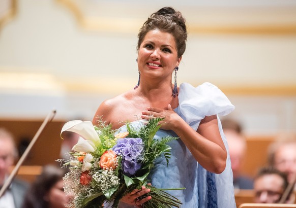 epa05513528 Russian soprano Anna Netrebko smiles holding a bouquet of flowers after her performance with Azerbaijani tenor Yusif Eyvazov (not in picture) at the Laeiszhalle in Hamburg, Germany, 28 Aug ...