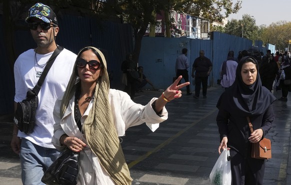 A woman flashes a victory sign as she walks around in the old main bazaar of Tehran, Iran, Saturday, Oct. 1, 2022. Thousands of Iranians have taken to the streets over the last two weeks to protest th ...