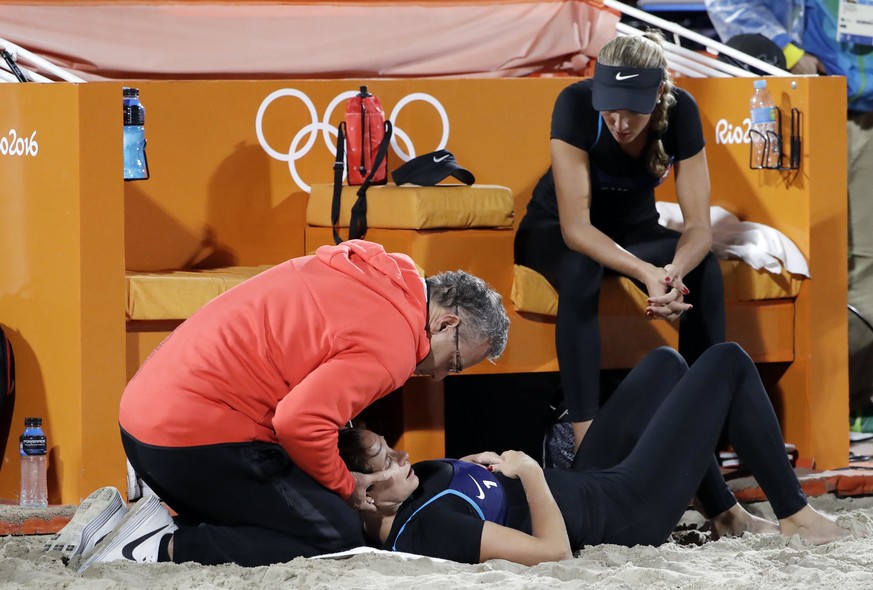 Switzerland&#039;s Isabelle Forrer, bottom, is tended to after an injury as teammate Anouke Verge-Depre, right, watches during a women&#039;s beach volleyball match against the United States at the 20 ...