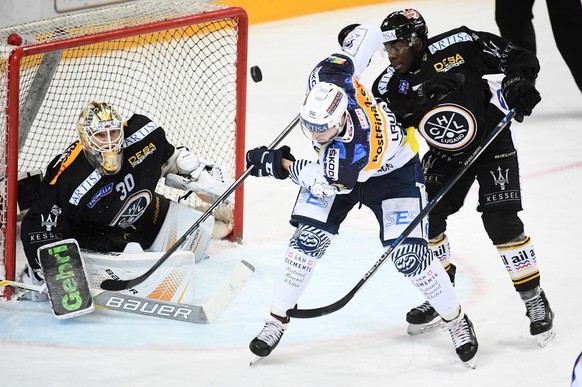 LuganoÕs goalkeeper Elvis Merzlikins, Ambri&#039;s player Adrien Lauper and Lugano&#039;s player Lucas Matewa, from left, fight for the puck, during the preliminary round game of National League Swiss ...