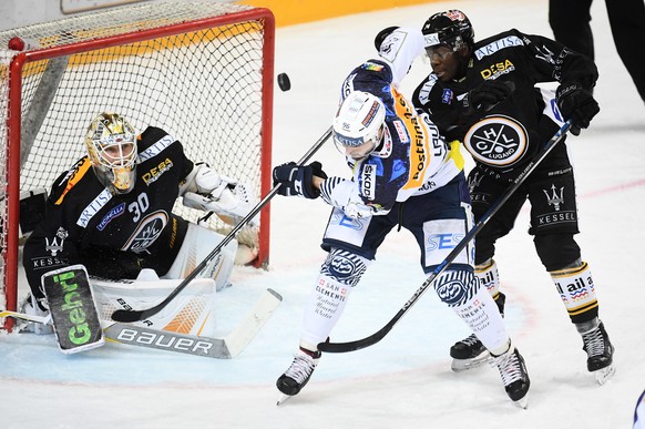 LuganoÃs goalkeeper Elvis Merzlikins, Ambri&#039;s player Adrien Lauper and Lugano&#039;s player Lucas Matewa, from left, fight for the puck, during the preliminary round game of National League Swis ...